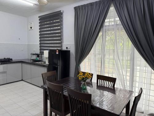 a kitchen with a dining room table with chairs and a large window at Wareesha Homestay, Corner Lot With Netflix in Padang Serai