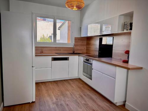 une cuisine avec des armoires blanches et une fenêtre dans l'établissement La bohème du clocher - Cosy calme hyper-centre 2 à 6 pers, à Bergerac