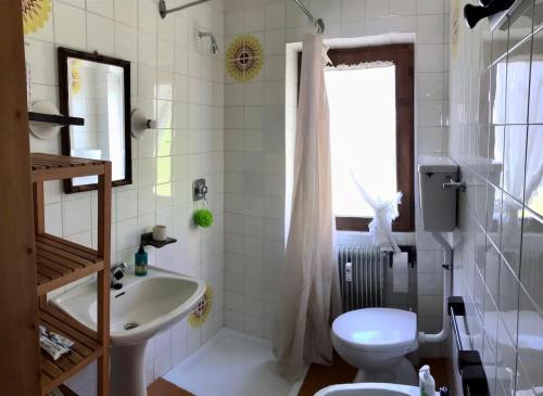 a white bathroom with a sink and a toilet at Appartamento Dolomiti con parcheggio privato coperto in Folgarida