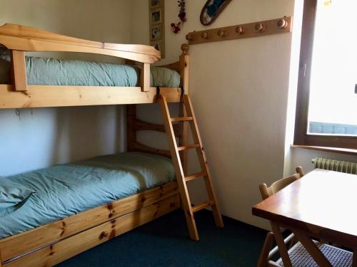 a bunk bed in a room with a ladder and a table at Appartamento Dolomiti con parcheggio privato coperto in Folgarida