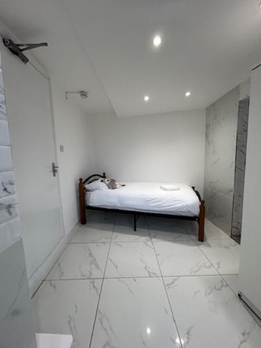 Ein weißes Zimmer mit einem Bett auf einem Fliesenboden. in der Unterkunft Park House Goodmayes, Ilford London in Goodmayes