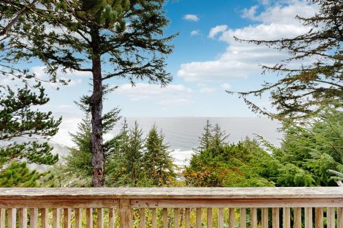 a wooden fence with trees and the ocean in the background at Cliffside Serenity in Oceanside