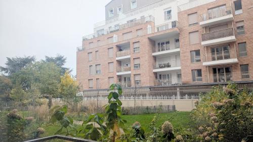 un gran edificio de ladrillo con un jardín delante de él en Cocon Colombes - close to La Défense and Paris, en Colombes