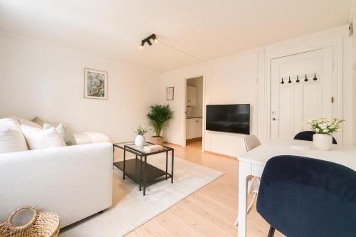 a living room with a white couch and a tv at Delightful Bryggen Apartment - Minimum Age 25 in Bergen
