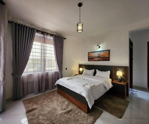 a bedroom with a large bed and a large window at Kisaasi Luxury Apartment in Kampala