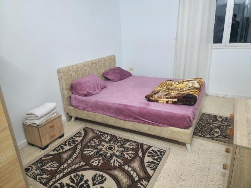 a bedroom with a bed with purple sheets and pillows at Mechi House in Djerba