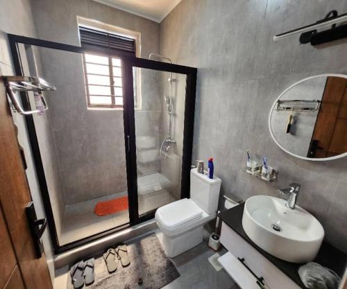 a bathroom with a toilet and a sink and a shower at Kisaasi Luxury Apartment in Kampala