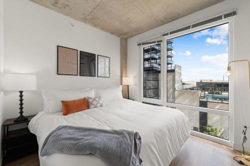 a bedroom with a white bed and a large window at Stylish 3BR Gem in Prime Location in Chicago