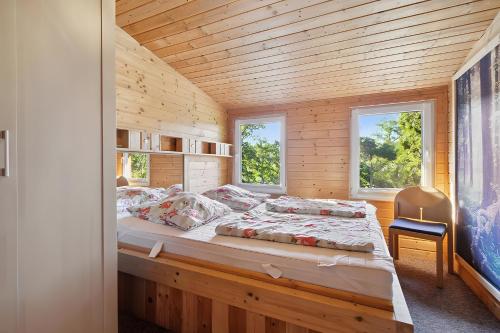 een bed in een houten kamer met 2 ramen bij Ferienhaus 249 - Haus Seeblick in Kleinwolschendorf
