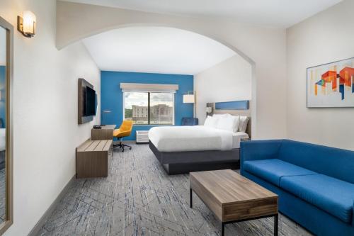 a hotel room with a bed and a blue couch at Holiday Inn Express Pratt by IHG in Pratt