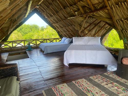 a bedroom with two beds in a thatched room at Pirita Beach House in Santa Ana