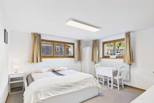 a white bedroom with a bed and a desk at Comfortable studio near Saas-Fee ideal for couples in Saas-Grund