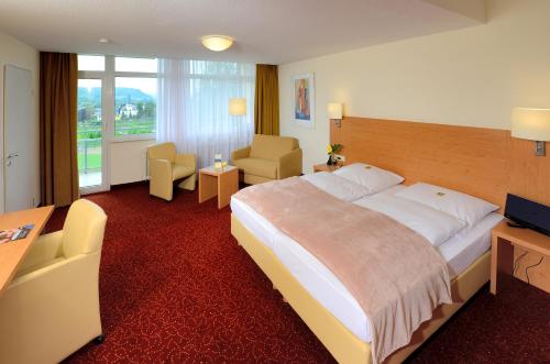 ein Hotelzimmer mit einem großen Bett und einem Schreibtisch in der Unterkunft Ringhotel Haus Oberwinter in Remagen