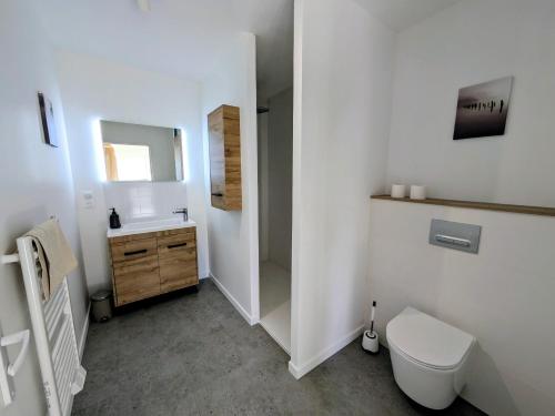a white bathroom with a toilet and a sink at La maison du petit large in La Bernerie-en-Retz