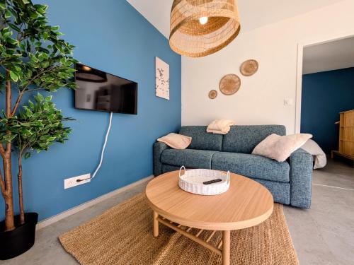a living room with a blue couch and a table at La maison du petit large in La Bernerie-en-Retz
