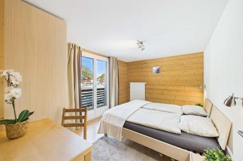 萨斯格伦德Family-friendly apartment with mountain views的一间卧室，配有一张床、一张书桌和一扇窗户