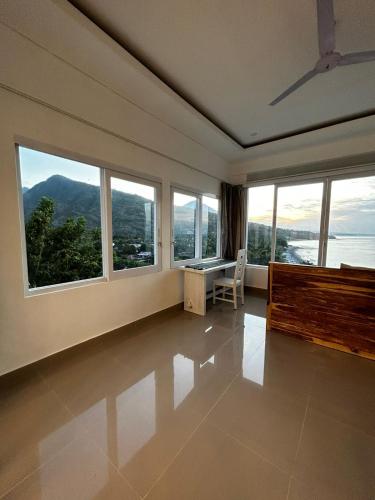 a room with large windows and a desk and a table at Waenis Sunset View Hotel and Restaurant, Amed, Bali in Amed