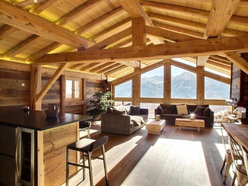 een woonkamer met een groot houten plafond met ramen bij Les Alpages du Soleil in La Rosière
