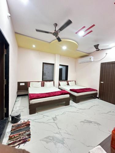 a bedroom with two beds and a ceiling fan at Hotel Krishna Raj in Ujjain