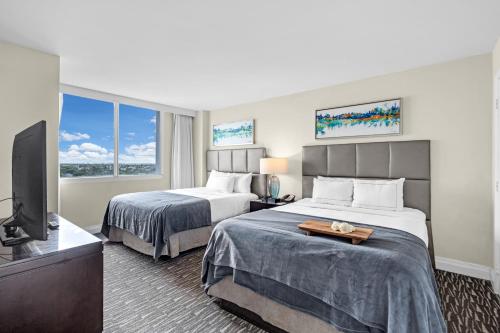 ein Hotelzimmer mit zwei Betten und einem Flachbildfernseher in der Unterkunft Gallery One Resort Access Fort Lauderdale Beach in Fort Lauderdale