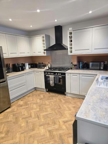 a kitchen with white cabinets and a stove top oven at 4 bed house close to Allianz Stadium, LHR and London 20mins away in Hounslow