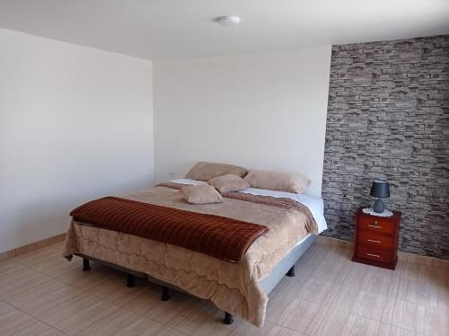 a bedroom with a bed and a brick wall at Casa en Atuntaqui in Atuntaqui