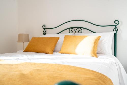 1 cama con sábanas blancas y almohadas de color naranja en Villa Mirage - by Madeira To Stay, en Arco da Calheta