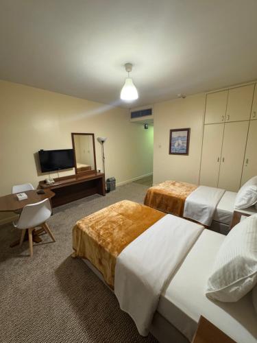 a hotel room with two beds and a flat screen tv at Top Hotel Apartments in Al Ain