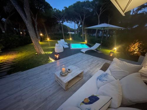 eine Terrasse mit einem Sofa, einem Sonnenschirm und einem Pool in der Unterkunft Villa Marghe in Budoni