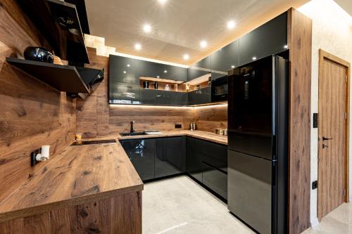 a kitchen with a black refrigerator and wooden walls at Beni Deluxe in Plovdiv
