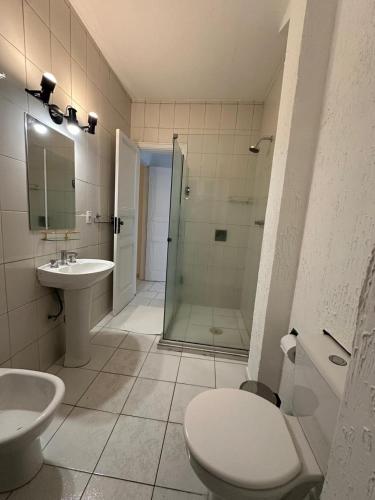 a bathroom with a shower and a toilet and a sink at Atlântico Hotel in Santos