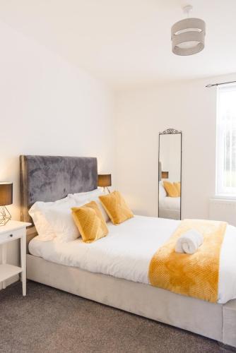 a white bedroom with a large bed and a mirror at Northumberland Cosy Home in Bedlington