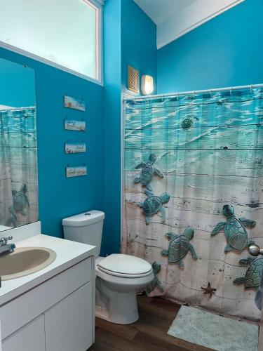 a bathroom with a toilet and a shower curtain with turtles at Sky Blue 321 in Cedar Key