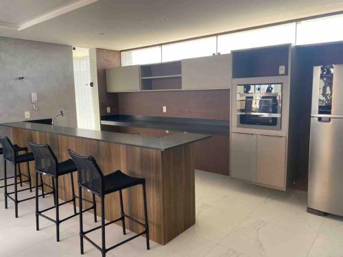 una cucina con bar, sgabelli e piano cottura di Flat encantador na praia de Intermares com piscina a Ilha da Restinga