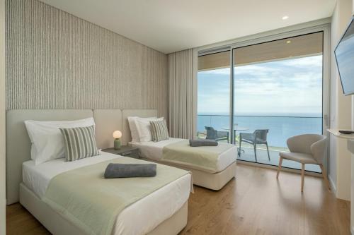 een slaapkamer met 2 bedden en uitzicht op de oceaan bij OurMadeira - GrandView Cristo Rei in Garajau