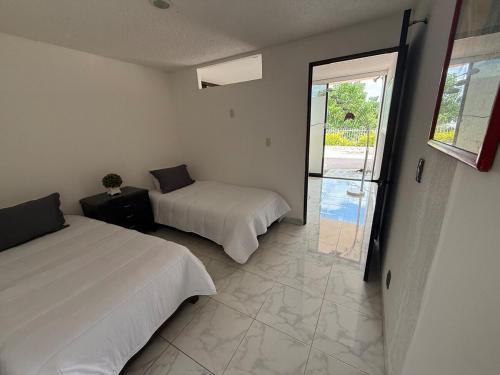 a bedroom with two beds and a sliding glass door at Suite La Lomita #3 Climatizada in Tuxtla Gutiérrez