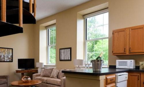 a living room with a couch and a kitchen with windows at Ledges Hotel in Hawley
