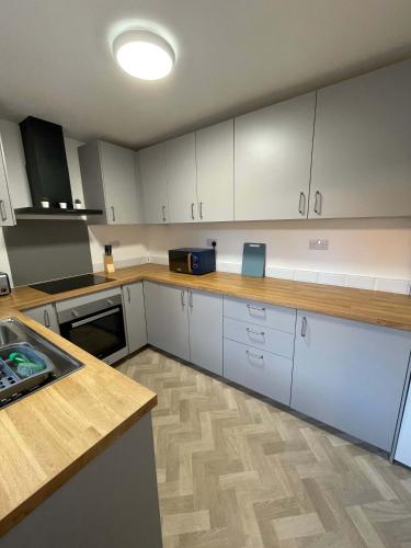 Una cocina con gabinetes blancos y una encimera de madera. en Alderson House, en Hartlepool