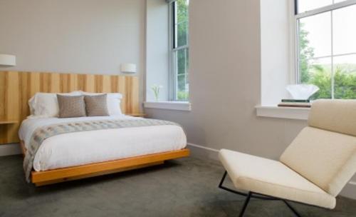 um quarto com uma cama, uma cadeira e janelas em Ledges Hotel em Hawley