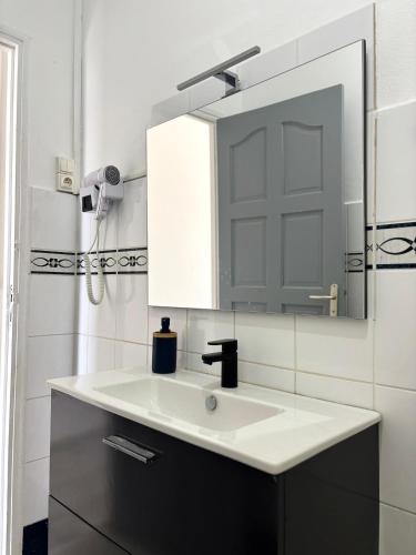 a bathroom with a white sink and a mirror at Le nid d'Emijulie - Maison familiale proche plage in Gourbeyre