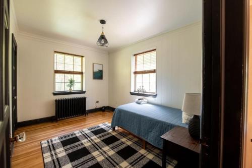 una camera con un letto blu e due finestre di The Minimalist Retreat a Safe Harbor