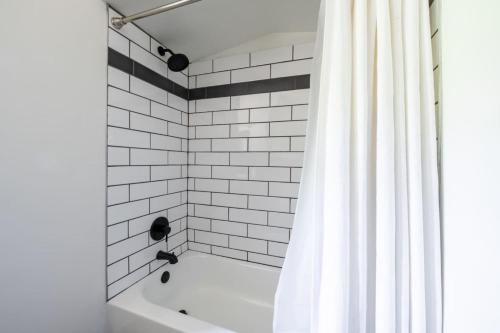 e bagno con vasca e tenda da doccia bianca. di The Minimalist Retreat a Safe Harbor