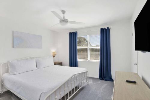 a bedroom with a bed and a window with blue curtains at Private Beach and Pool in Gulf Shores