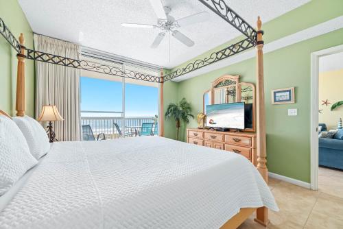 ein Schlafzimmer mit einem weißen Bett und einem Fernseher in der Unterkunft Beach Club Doral 504 in Gulf Highlands