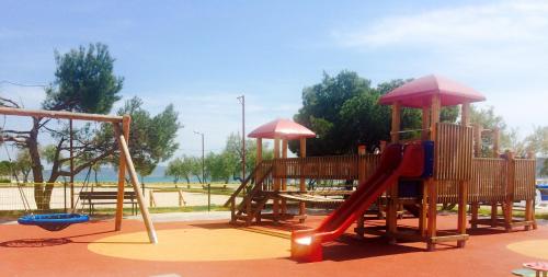 - un parc avec une aire de jeux dotée d'un toboggan et d'un parasol dans l'établissement Primasrima Apartments, à Vodice
