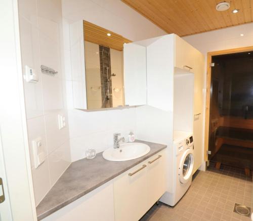 a bathroom with a sink and a washing machine at Convenient Apartment for 2 with Sauna in Pori