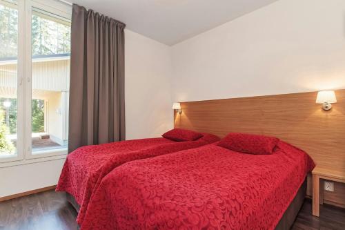 een slaapkamer met een bed met een rood dekbed en een raam bij Spacious Apartment for 6 with Sauna in Harviala