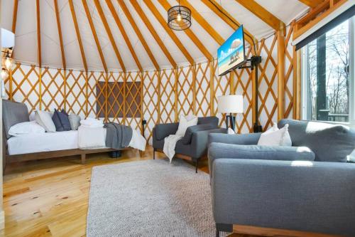 a yurt with couches and a bed and a tv at Adventure Abode - Modern Yurt in Brookville