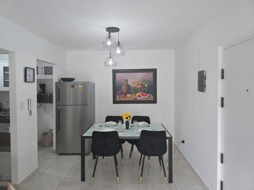 a dining room table with chairs and a refrigerator at Apartamento palmera del este 3 in La Javilla