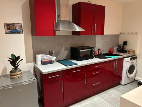 a kitchen with red cabinets and a microwave at Grand studio refait à neuf in Vierzon